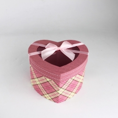 結婚式のための弓とピンクのハート形の段ボール箱